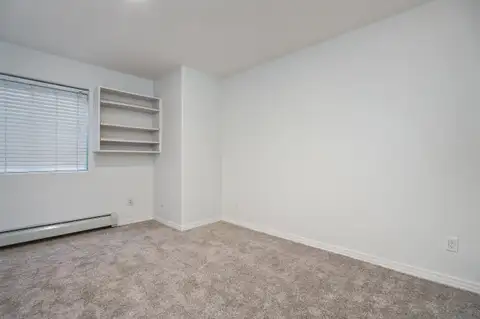 Bedroom with built-in open shelving, new carpet and baseboard heat