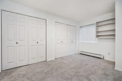 Bedroom with two sets of bifold closet doors and built-in shelves