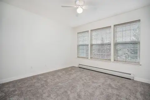 Bedroom with a row of three windows, new carpet and a ceiling light