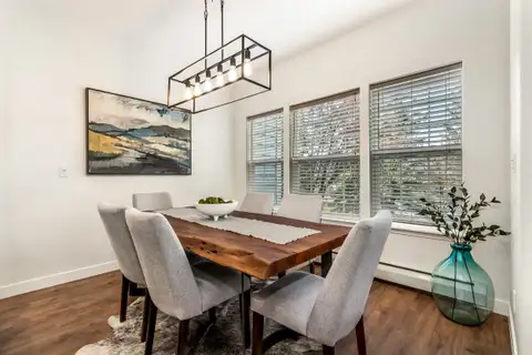 Dining room with a black linear pendant light, wood table and three windows