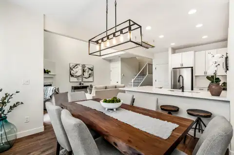 Dining room looking into the kitchen and living area, with a linear pendant over the table