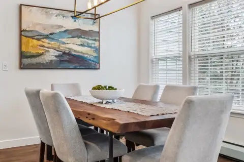 Dining area with a wood table, upholstered chairs and a wall of windows