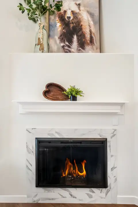 Gas fireplace with a marble-look tile surround and white mantel