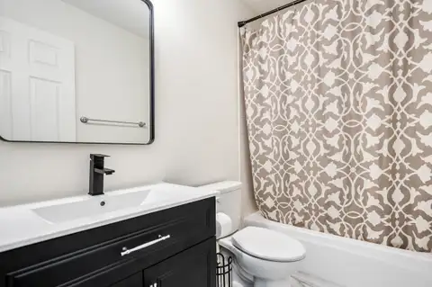 Guest bathroom with a black vanity, integrated sink, black faucet and tub-shower