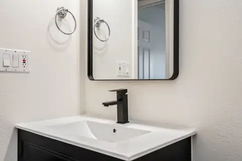 Black vanity with an integrated white sink, black faucet and black-framed mirror