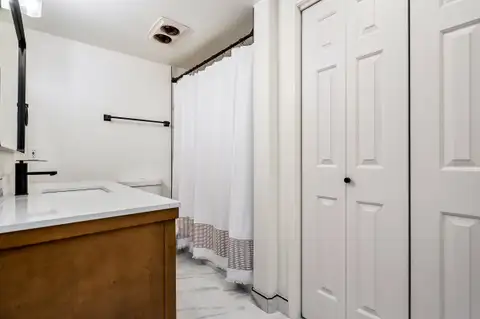 Hall bathroom with a wood vanity, tile floor and linen closet