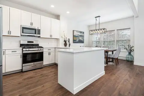 Remodeled kitchen with white shaker cabinets, a center island, stainless range and a dining area by the windows