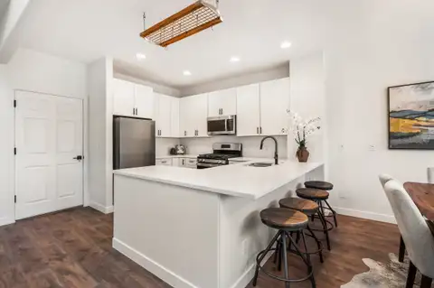 Kitchen peninsula with bar stools, recessed lighting and white cabinets to the ceiling