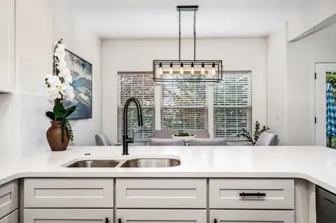 Kitchen peninsula with an undermount double sink and black faucet facing the dining room