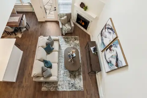 Living room seen from the loft above, with plank flooring and the corner fireplace