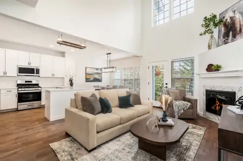 Open living room and kitchen with a high ceiling, corner fireplace and wood-look plank floors
