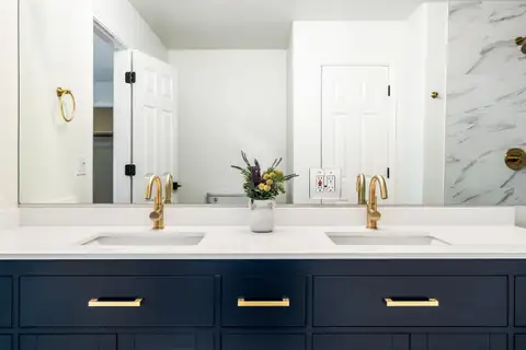 Double vanity with two undermount sinks, brass faucets and a wide mirror